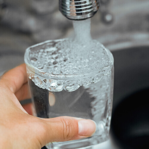 A stream of water flows into a glass cup